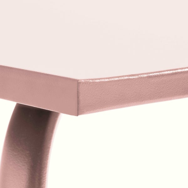 Nahaufnahme einer Tischecke mit einem geschwungenen Metallbein und einer strukturierten Oberfläche.