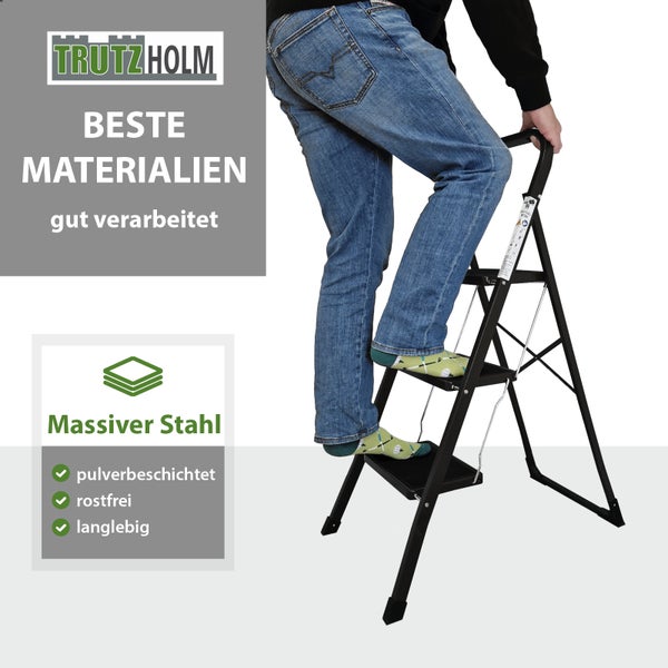 Eine Person steigt auf eine stabile Trutzholm Stahl Haushaltsleiter mit drei Stufen und rutschfesten Trittflächen.