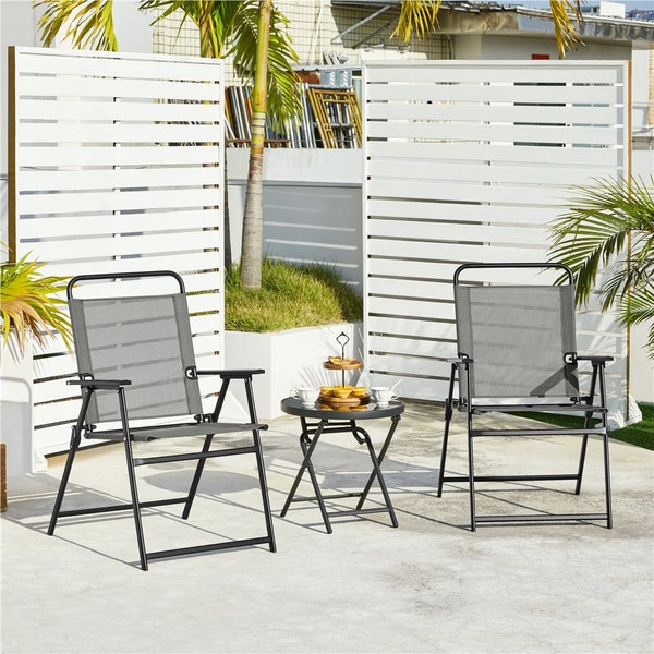 Zwei schwarze Klappsessel mit grauem Textilgewebe und ein kleiner runder Beistelltisch auf einer hellen Terrasse vor weißen Sichtschutzwänden.