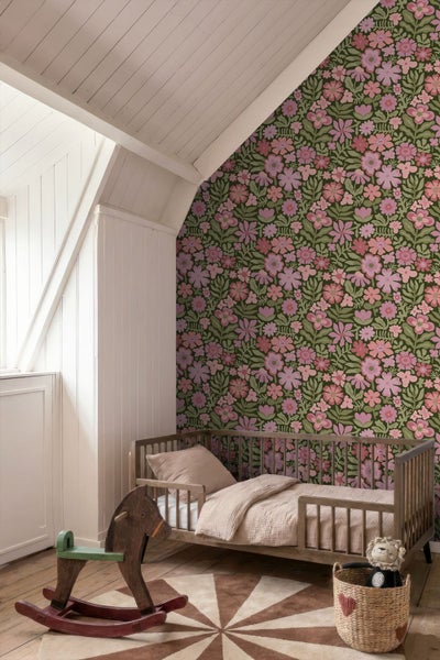 Kinderzimmer mit Blumentapete, Holzbett und Schaukelpferd unter einer Dachschräge.