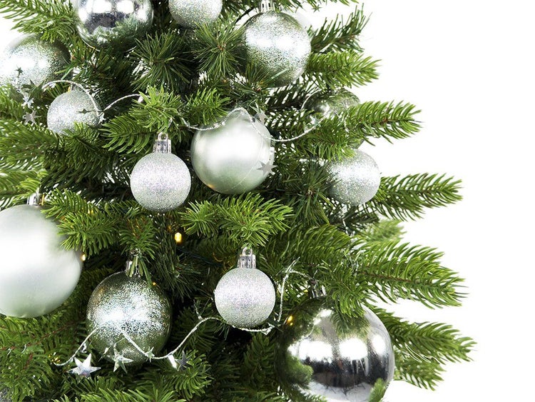 Künstlicher Weihnachtsbaum mit silbernem Weihnachtsschmuck wie Christbaumkugeln und einer Lichterkette mit Sternen.