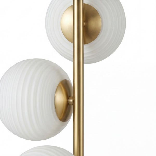 Detailansicht einer Leuchte mit messingfarbenem Metallstab und weißen geriffelten Glaskugeln