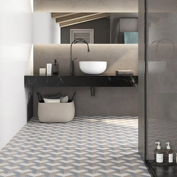 Modernes Badezimmer mit gemusterten Bodenfliesen, wandhängendem Waschbecken, schwarzer Armatur und großem Spiegel in minimalistischem Design.