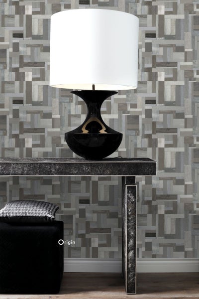 Dekorative Szene mit Tischleuchte, Konsole und Hocker vor einer Wand mit Holzblockmuster.