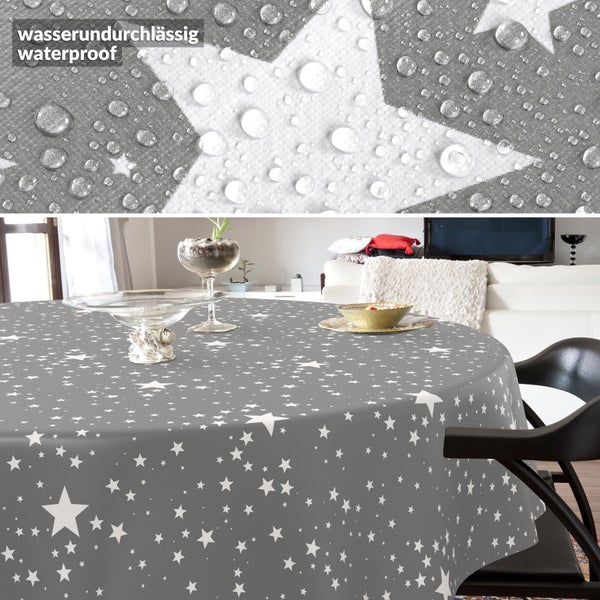 Runde Tischdecke mit Sternenmuster in einem Wohnzimmer, Detailaufnahme der wasserundurchlässigen Oberfläche mit Wassertropfen.