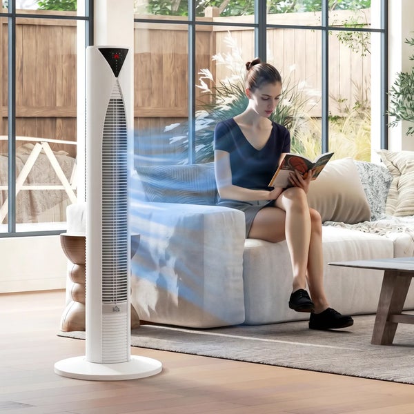Turmventilator in einem modernen Wohnzimmer mit einer auf dem Sofa sitzenden Frau, die ein Buch liest.