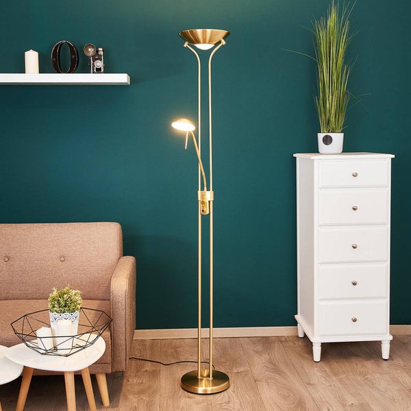 Goldene Stehleuchte mit Deckenfluter und verstellbarem Lesearm in einem modernen Wohnzimmer mit Sofa und weißer Kommode.