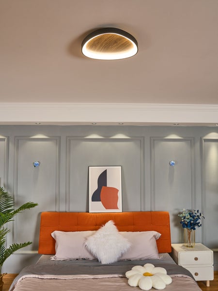 Runde Deckenleuchte mit schwarzem Rand und Holz-Dekor in einem modernen Schlafzimmer mit Wandpaneelen und orangefarbenem Bett.