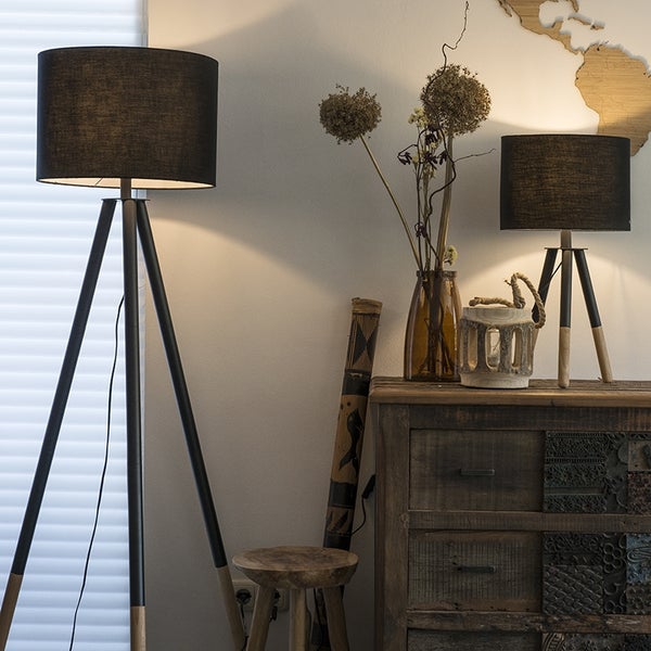 Wohnzimmer mit Stativstehleuchte und Tischleuchte, die beide einen Textilschirm und ein Holzgestell haben, neben einer rustikalen Kommode.