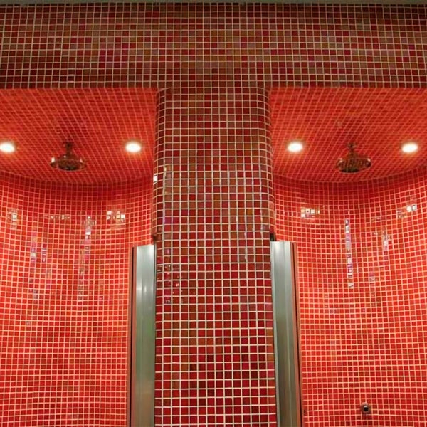 Duschbereich mit Mosaikfliesen an gewölbten Wänden und an einer mittigen Säule sowie zwei integrierten Duschköpfen in einer modernen Nasszelle