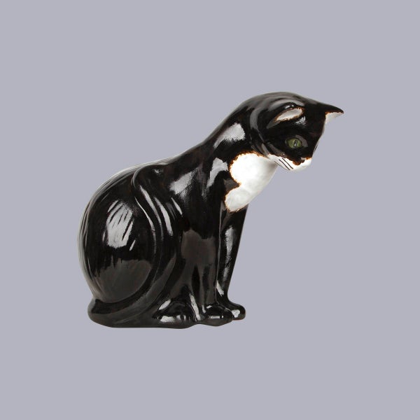 Sitzende Katzenfigur aus glänzender Keramik in Schwarz und Weiß.