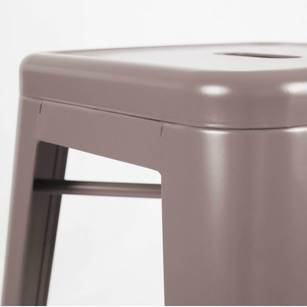 Nahaufnahme eines Metallhockers mit abgerundeten Kanten und einer horizontalen Verstrebung.