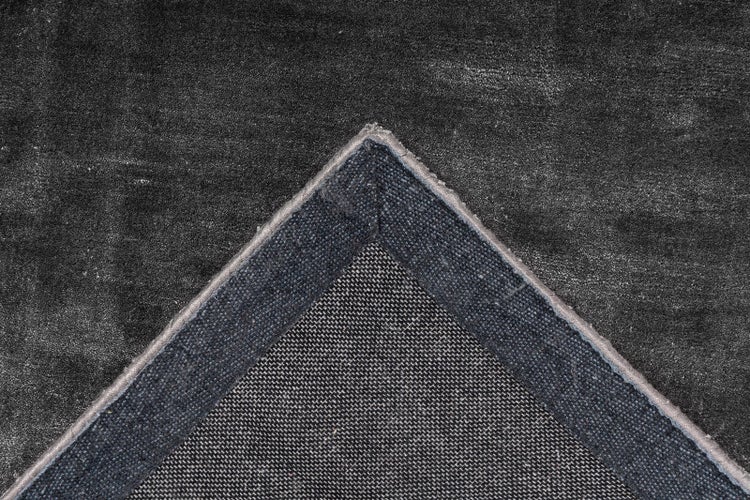 Detailansicht einer umgeschlagenen Teppichecke mit sichtbarer gewebter Rückseite und weichem Flor.