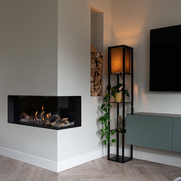 Wohnzimmer mit Kamin, Holzregal, Stehlampe und Medienschrank