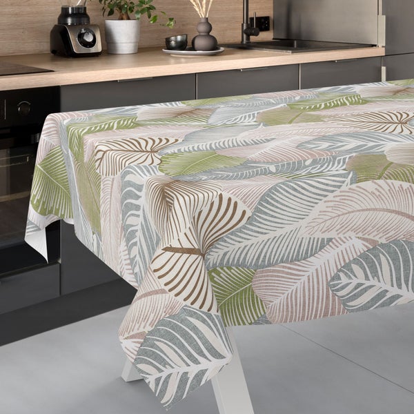 Tischdecke mit Blattmuster auf einem Tisch in einer hellen, modern eingerichteten Küche mit Arbeitsplatte und Pflanze.