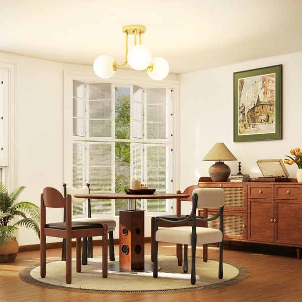 Helles, organisiertes Esszimmer mit rundem Holztisch, verschiedenen Stühlen, einer modernen Deckenleuchte mit drei Glaskugeln und einem Holzsideboard.