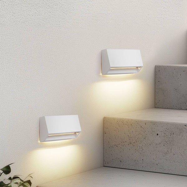 Zwei moderne LED-Wandleuchten an einer strukturierten Wand neben einer Betontreppe mit warmem, nach unten gerichtetem Licht.