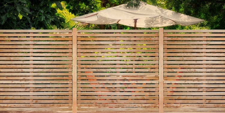 Holzzaun mit Sonnenschirm im Garten