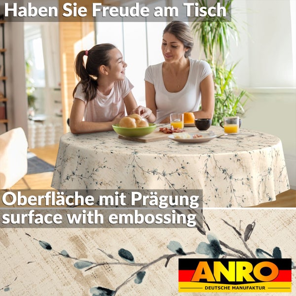 Rundes Wachstuch mit floralem Zweigmuster und geprägter Oberfläche an einem gedeckten Tisch mit zwei Personen. ANRO Logo.