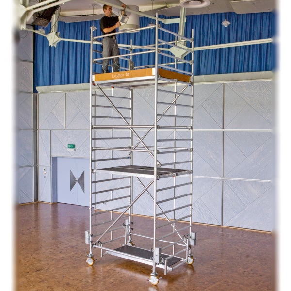 Ein Bauarbeiter auf einem Layher Fahrgerüst bei Reparaturarbeiten in einem Raum.