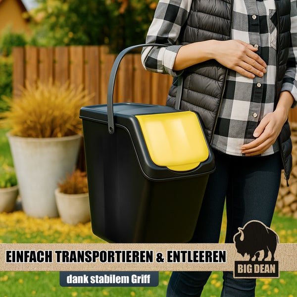 Eine Frau trägt einen schwarzen Komposteimer mit gelbem Deckel und stabilem Griff im Garten.