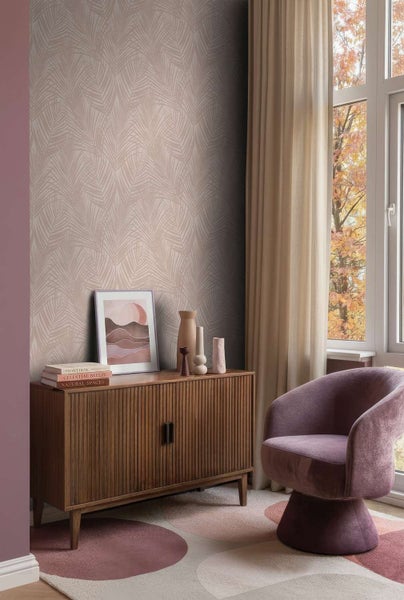 Wohnzimmer mit Vliestapete mit Palmenblattmuster, Sideboard aus Holz, gepolstertem Sessel und gemustertem Teppich vor einem großen Fenster.