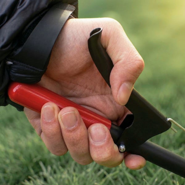 Hand am ergonomischen Griff eines Greifwerkzeugs über dem Rasen.