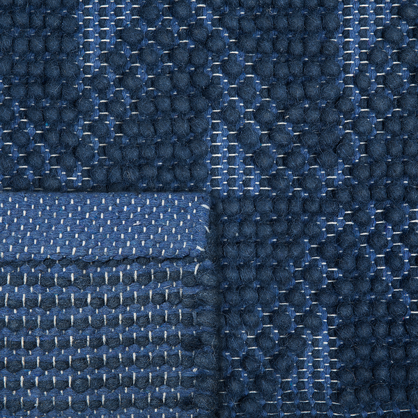 Nahaufnahme eines blauen Webteppichs mit Noppenstruktur und geometrischem Muster.