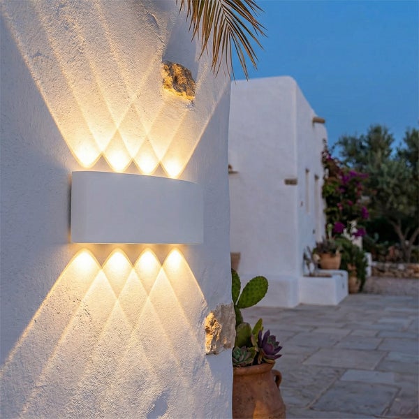 Weiße LED-Außenwandleuchte mit Up-und-Down-Lichteffekt, der ein Rautenmuster auf eine strukturierte Wand wirft.