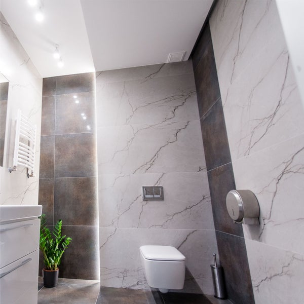 Modernes Badezimmer mit Fliesen in Marmoroptik, Toilette, Waschbecken und Handtuchwärmer.
