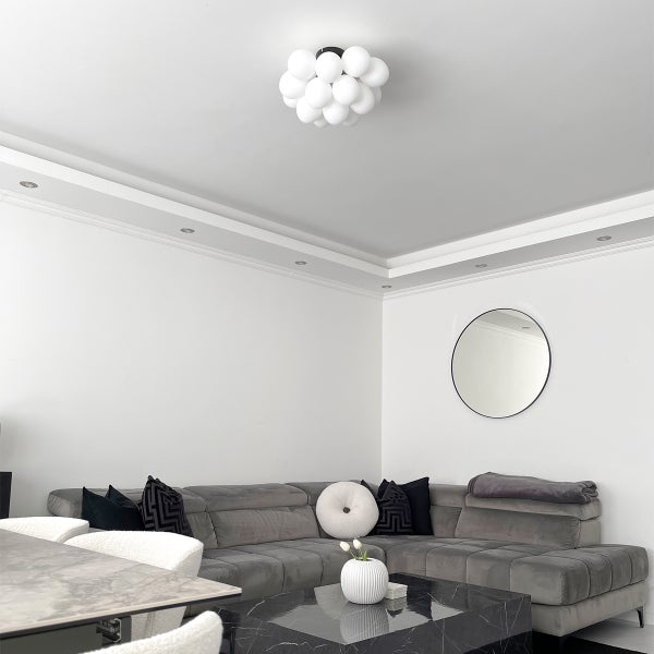 Wohnzimmer mit grauer Eckcouch, Couchtisch aus Marmor und runder Deckenleuchte