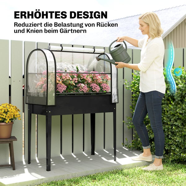 Frau bewässert Blumen in einem ergonomischen Hochbeet mit transparenter Abdeckung für rückenschonendes Gärtnern.