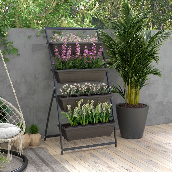 Vertikales Pflanzregal mit vier Etagen aus Metall und Kunststoff, bestückt mit Blumen auf einer Holzterrasse vor einer Betonwand.