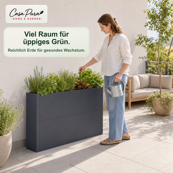 Eine Frau pflegt Kräuter in einem großen, anthrazitfarbenen Hochbeet auf einer modernen Terrasse.