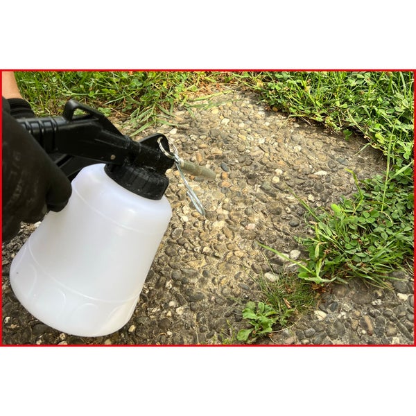 Nahaufnahme eines Unkrautvernichters mit Sprühvorrichtung auf einer Steinoberfläche mit Bewuchs.