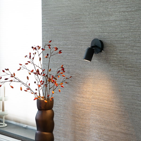 Wandleuchte im Raum mit Vase und Zweigen an der Wand