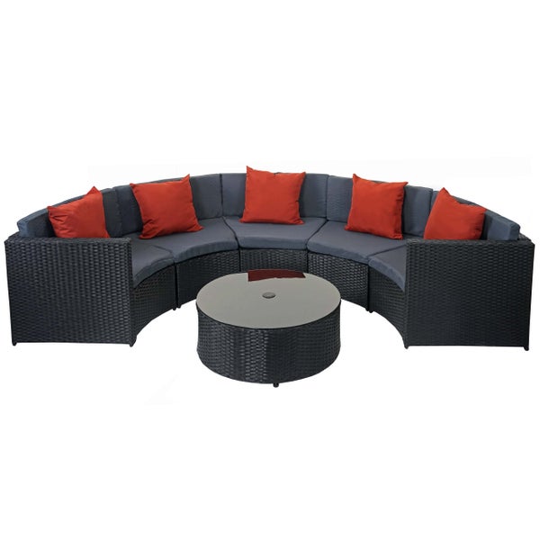 Halbkreisförmiges Lounge-Set aus Polyrattan mit Sitzkissen, roten Dekokissen und rundem Tisch mit Glasplatte.