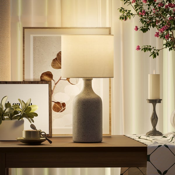 Dekoratives Interieur mit Tischlampe, Pflanzen, Kerzenständer und Bildern