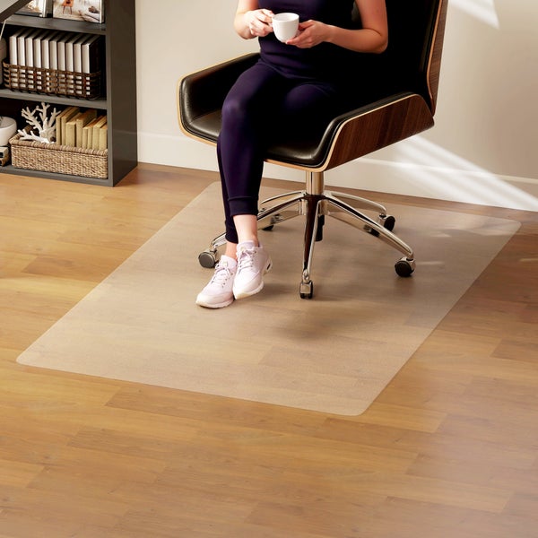 Transparente Bodenschutzmatte für Hartböden unter einem Bürostuhl auf Laminat in einem hellen Büro.