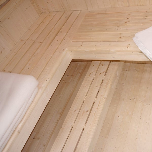 Innenansicht einer finnischen Sauna mit hellen Holzsaunabänken aus Fichtenholz und weißen Handtüchern.