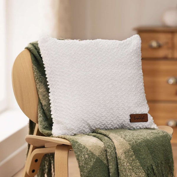 Dekokissen mit Kuschelzeit-Etikett auf einem Stuhl mit Decke