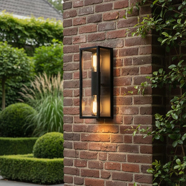 Moderne rechteckige Außenwandleuchte mit schwarzem Rahmen und zwei Filament-Leuchtmitteln an einer Backsteinwand in einem Garten.