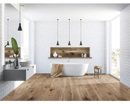 Badezimmer mit Badewanne, Waschbecken, Spiegel, Holzfußboden und Backsteinwand