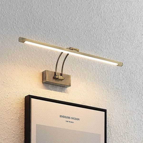 LED-Bilderleuchte in Altmessing-Optik, wandmontiert über einem Bild.
