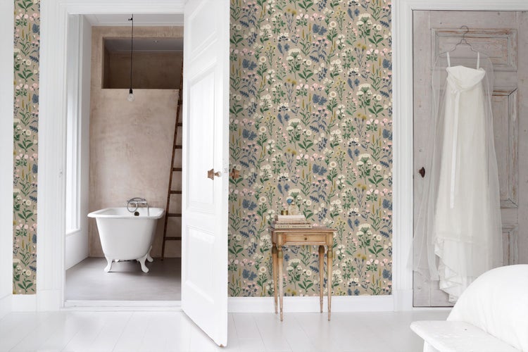 Helles Zimmer mit Vliestapete mit Wiesenblumenmuster, kleinem Holztisch und offener Tür zum Badezimmer mit freistehender Badewanne.