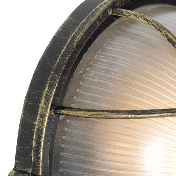 Nahaufnahme einer ovalen Außenwandleuchte mit geriffeltem Glas und einem schützenden Metallgitter im Patina-Look.