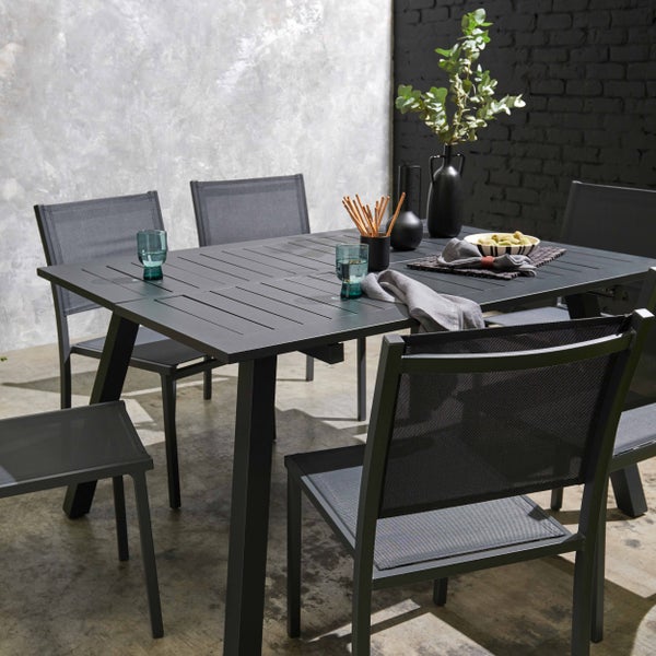 Modernes Gartenmöbel-Set mit ausziehbarem Aluminiumtisch mit Lattenplatte und passenden Textilnetz-Stühlen in minimalistischem Außenbereich.