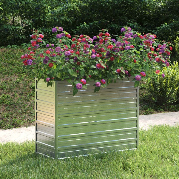 Hochbeet aus Metall mit horizontaler Riffelung, bepflanzt mit Blumen auf einer Rasenfläche in einem Garten.