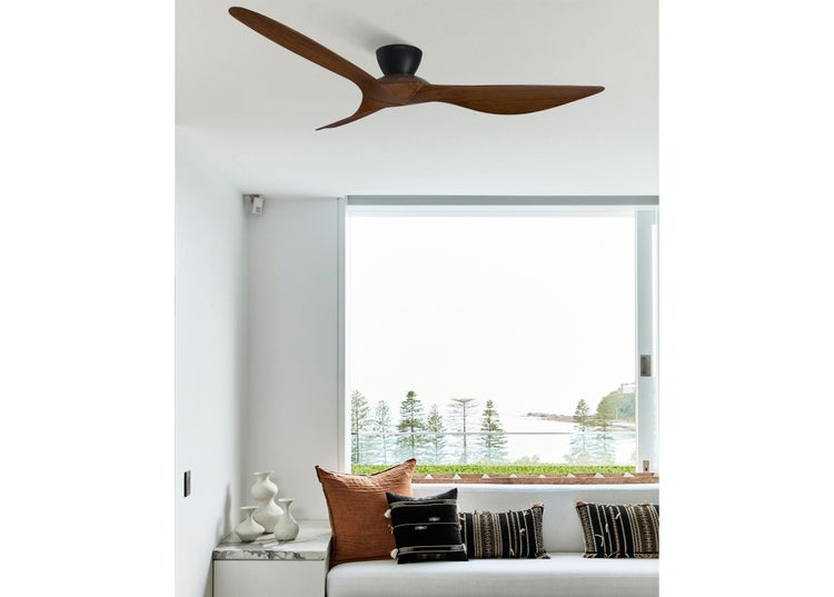 Deckenventilator mit drei Holzflügeln in einem modernen, hellen Wohnraum mit Blick auf das Meer.