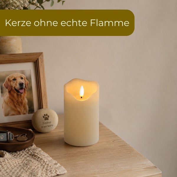 LED-Kerze ohne echte Flamme auf einem Holztisch neben einem Hundefoto und Gedenkobjekten.